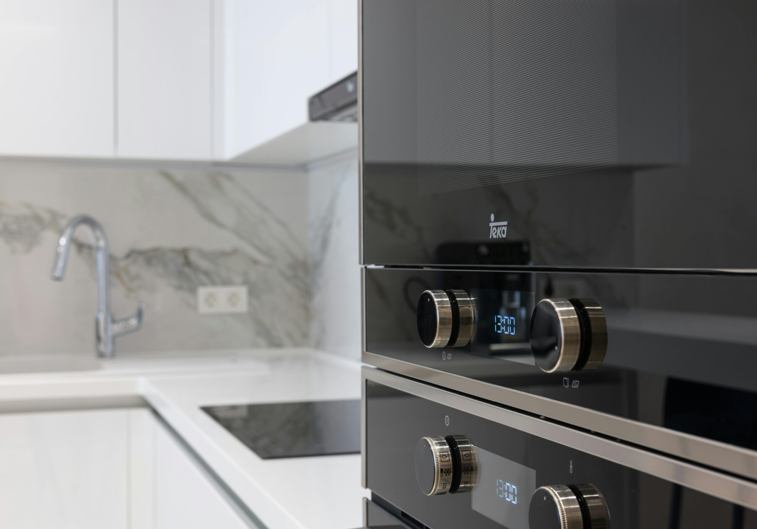 Interior of contemporary kitchen with stainless white surface induction cooker and electronic stove in modern apartment